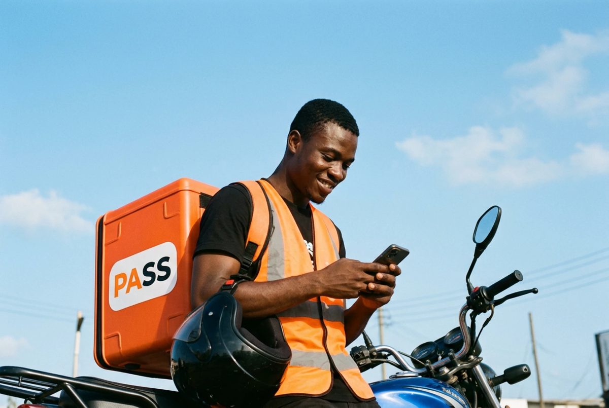 A PASS rider leaning on his bike, helmet off, checking his phone